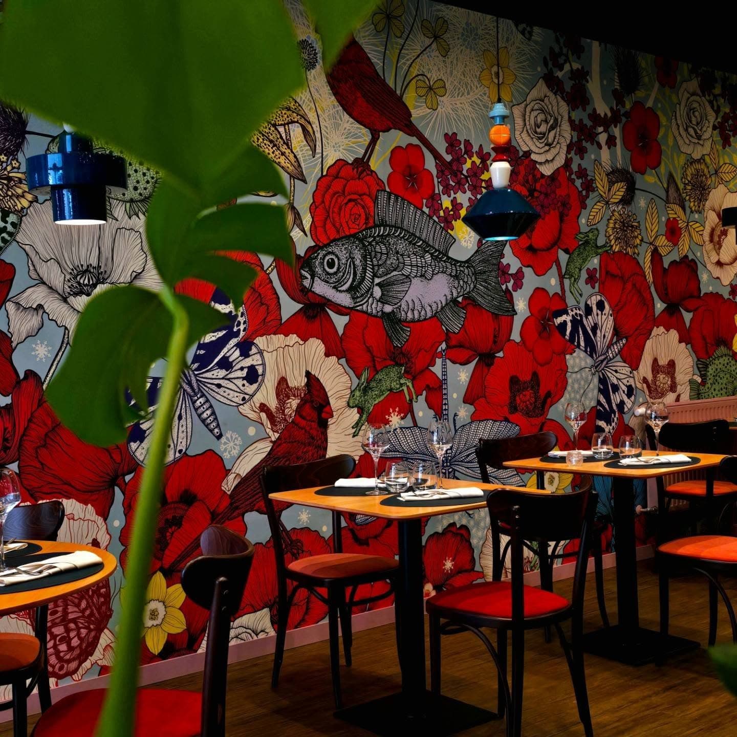 La salle du restaurant L'Adresse à Dole et sa grande fresque florale : coquelicots, oiseaux et suspensions colorées