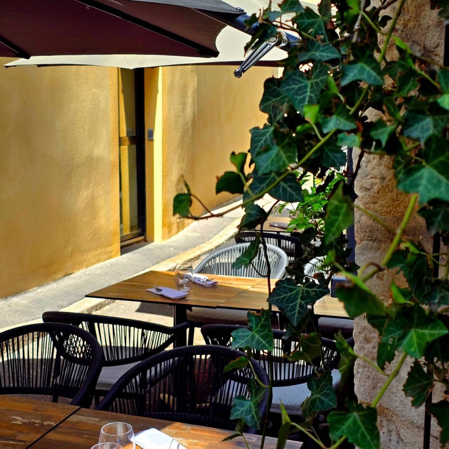 La terrasse du restaurant L'Adresse à Dole sous les parasols et le lierre, dans la ruelle de l'Orveau